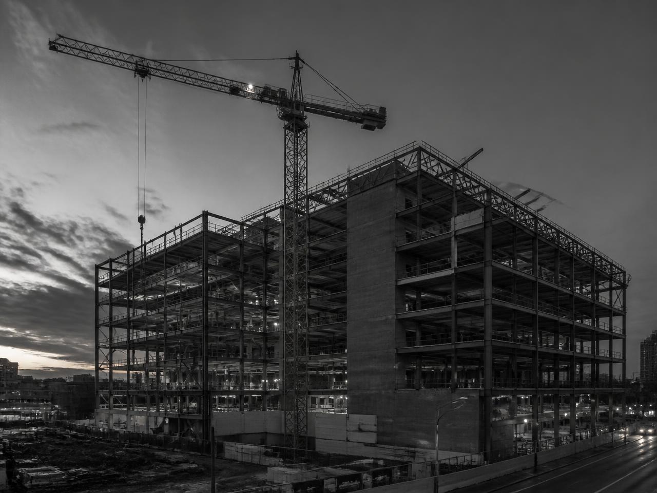 Turn comercial cu structură metalică în construcție la amurg, cu o macara turn